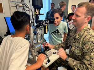 Lt. Trey Ketchum, an optometrist at U.S. Naval Hospital Guantanamo Bay, demonstrates the use of a slit lamp biomicroscope to students from W.T. Sampson Elementary and High School during a field trip, March 10, 2026. Student Noah Calvo looks through the biomicroscope to examine a classmate’s eye as part of the hands-on learning experience. The visit was part of an educational outreach initiative by U.S. Navy Medicine Readiness and Training Command Guantanamo Bay to introduce students to careers in military medicine. (U.S. Navy photo by Emily McCamy)