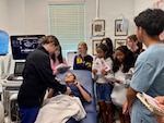Hospital Corpsman 3rd Class Lillian Pfeiffer demonstrates ultrasound technology to students from W.T. Sampson Elementary and High School during a field trip to U.S. Naval Hospital Guantanamo Bay, March 10, 2026. The hands-on demonstration introduced students to obstetric and gynecological care and provided a live look at ultrasound imaging. The visit was part of an educational outreach initiative by U.S. Navy Medicine Readiness and Training Command Guantanamo Bay to introduce students to careers in military medicine. (U.S. Navy photo by Emily McCamy)