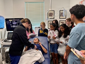 Hospital Corpsman 3rd Class Lillian Pfeiffer demonstrates ultrasound technology to students from W.T. Sampson Elementary and High School during a field trip to U.S. Naval Hospital Guantanamo Bay, March 10, 2026. The hands-on demonstration introduced students to obstetric and gynecological care and provided a live look at ultrasound imaging. The visit was part of an educational outreach initiative by U.S. Navy Medicine Readiness and Training Command Guantanamo Bay to introduce students to careers in military medicine. (U.S. Navy photo by Emily McCamy)