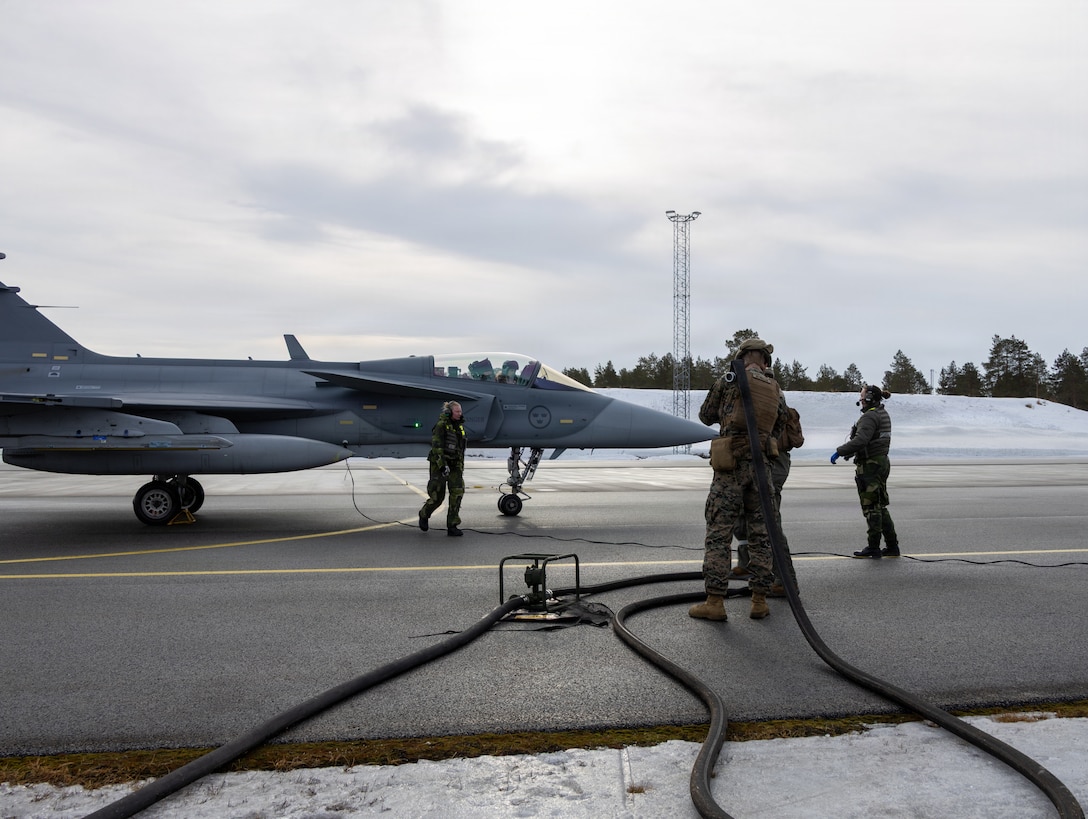 U.S. Marines with Marine Wing Support Squadron (MWSS) 273, Marine Air Control Group 28, 2nd Marine Aircraft Wing, and Swedish soldiers with the 32nd Intelligence Battalion refuel a Swedish JAS-39 Gripen at Kallax Air Base, Luleå, Sweden, March 13, 2026. MWSS-273 conducted forward arming and refueling point operations to support NATO air operations during exercise Cold Response 26. A key component of NATO's enhanced vigilance activity Arctic Sentry, exercise Cold Response 26 is a Norwegian-led winter military exercise designed to enhance collective defense capabilities and ensure U.S. readiness to rapidly deploy and seamlessly operate alongside NATO Allies in challenging arctic conditions. (U.S. Marine Corps photo by Lance Cpl. Donovan Pimentel)