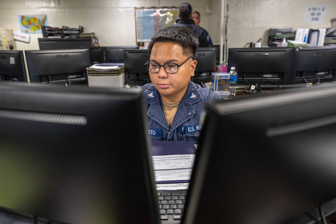 Personnel Specialist 3rd Class Bryan Costo updates administrative paperwork aboard the Nimitz-class aircraft carrier USS George H.W. Bush
