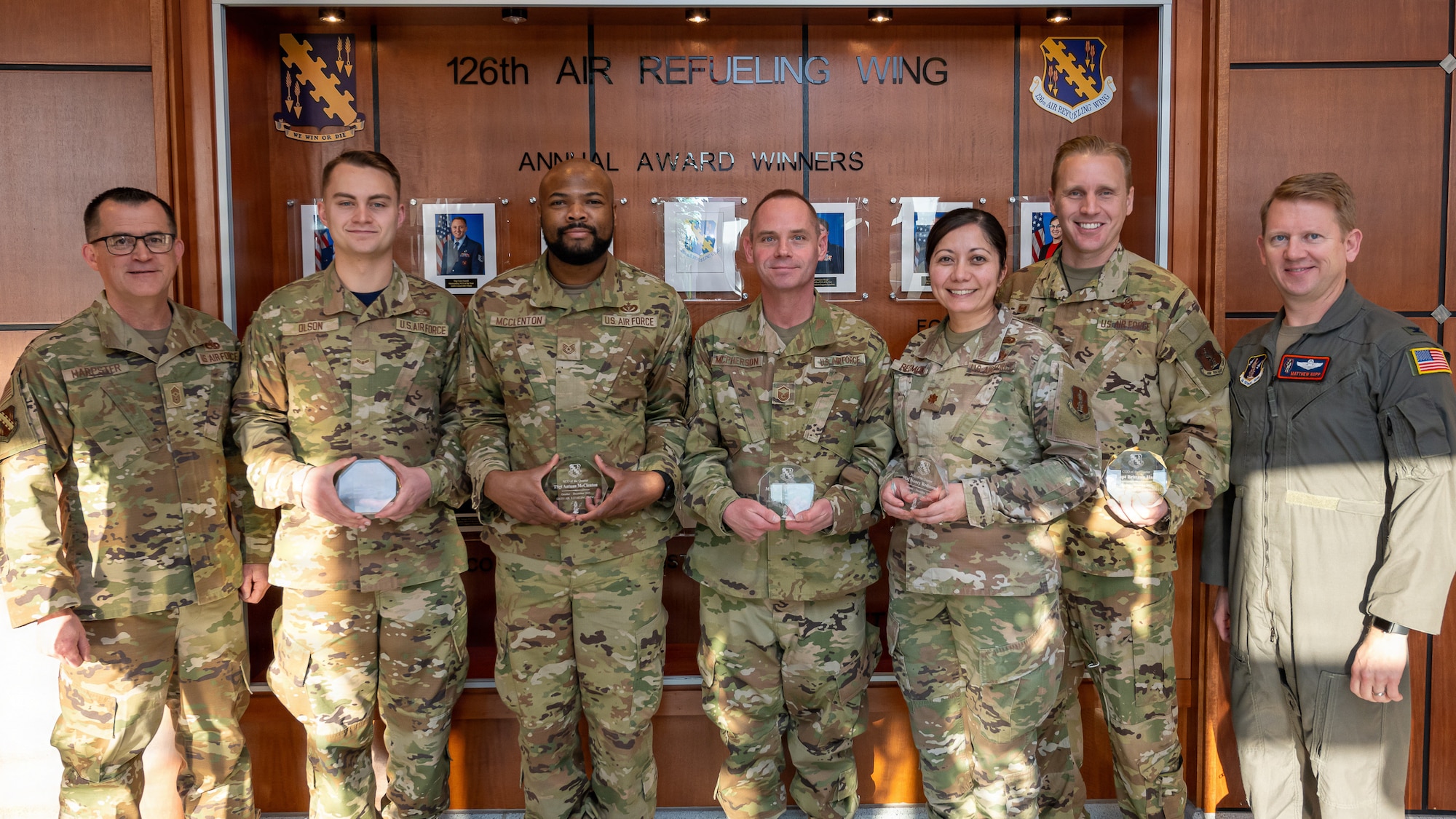 7 Airmen pose, 6 camouflage 1 in a flight suit 4 each holding an award