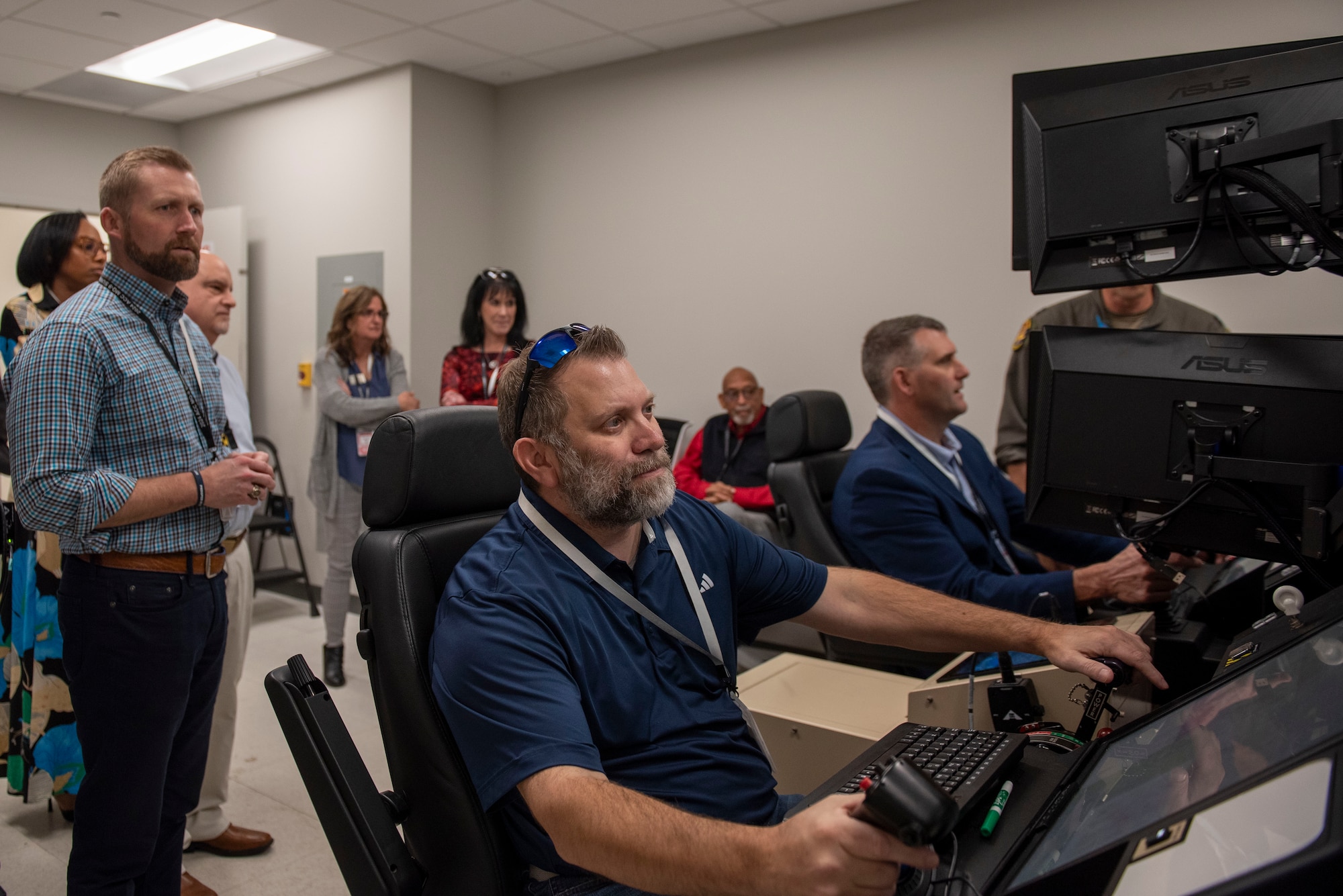 Josh Morrell, Sumter Chamber of Commerce director of partner development, center, and David Merchant, City of Sumter mayor, right, operate a Ground Control Station simulator at Shaw Air Force Base, S.C., March 9, 2026.