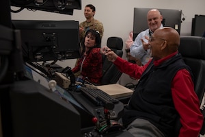 From left, Kim Hatchell, 20th Fighter Wing honorary commander, and James McCain Jr., Sumter County chairman, District 6, fist-bump while operating a Ground Control Station simulator during a tour hosted by the 25th Attack Wing at Shaw Air Force Base, S.C., March 9, 2026.