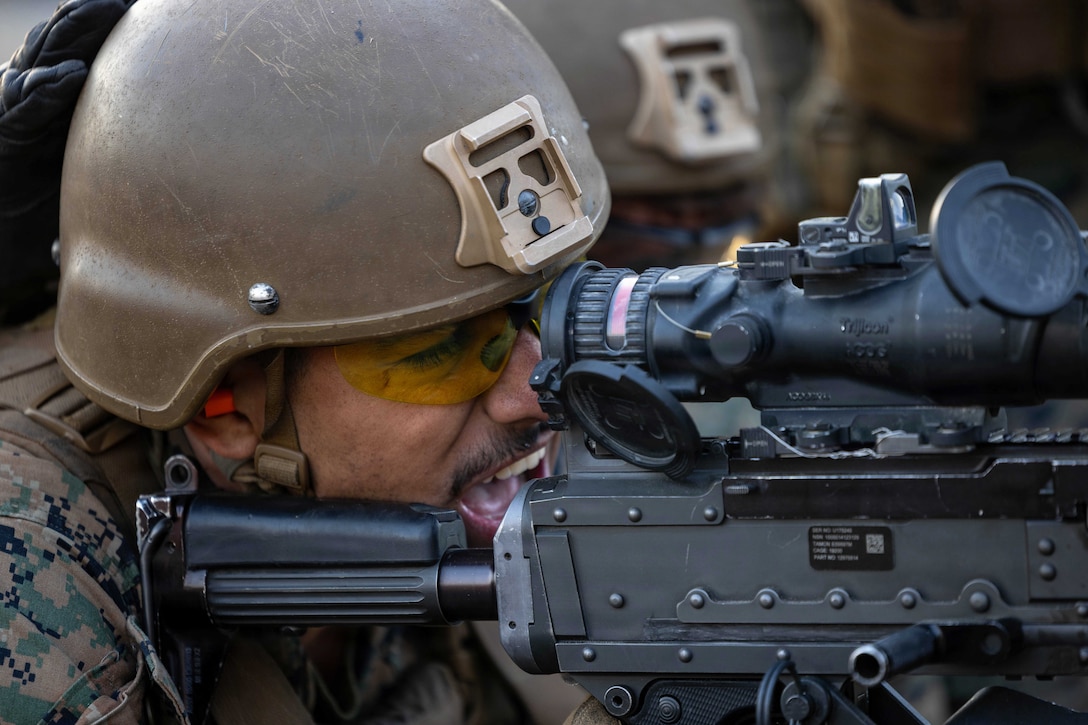 A close-up of a Marine in tactical gear firing a weapon.