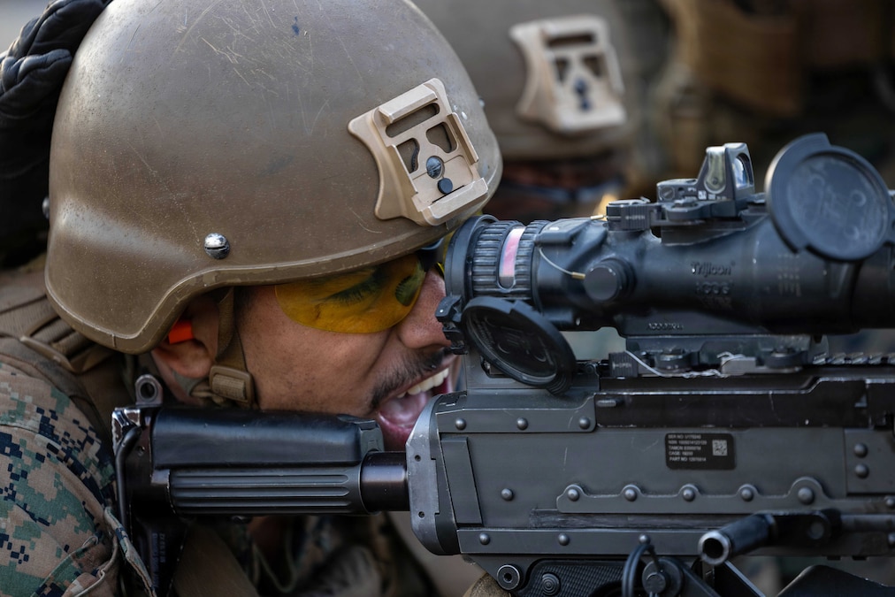 A close-up of a Marine in tactical gear firing a weapon.