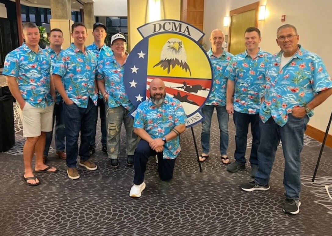 A group of people wearing matching blue Hawaiian shirts pose for a photo.