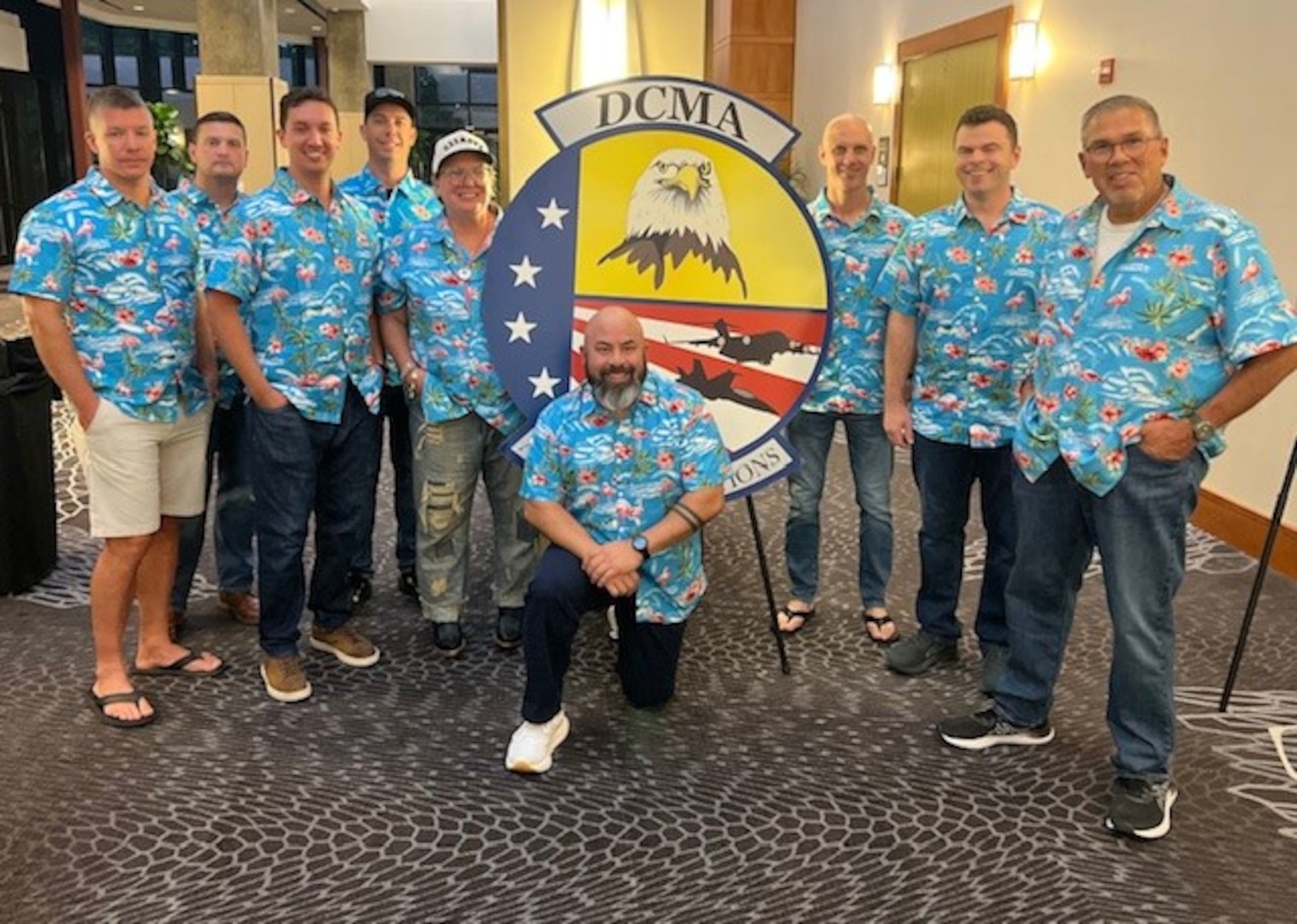 A group of people wearing matching blue Hawaiian shirts pose for a photo.