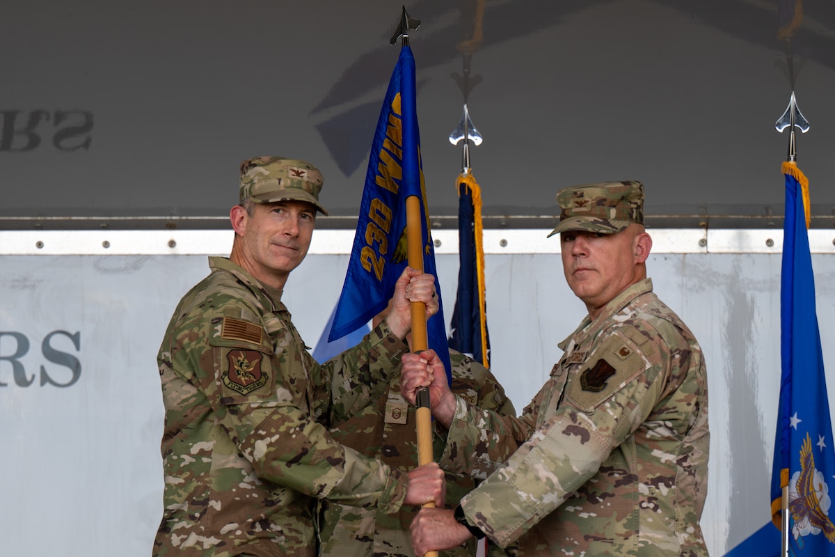 Man hands a guidon to another.