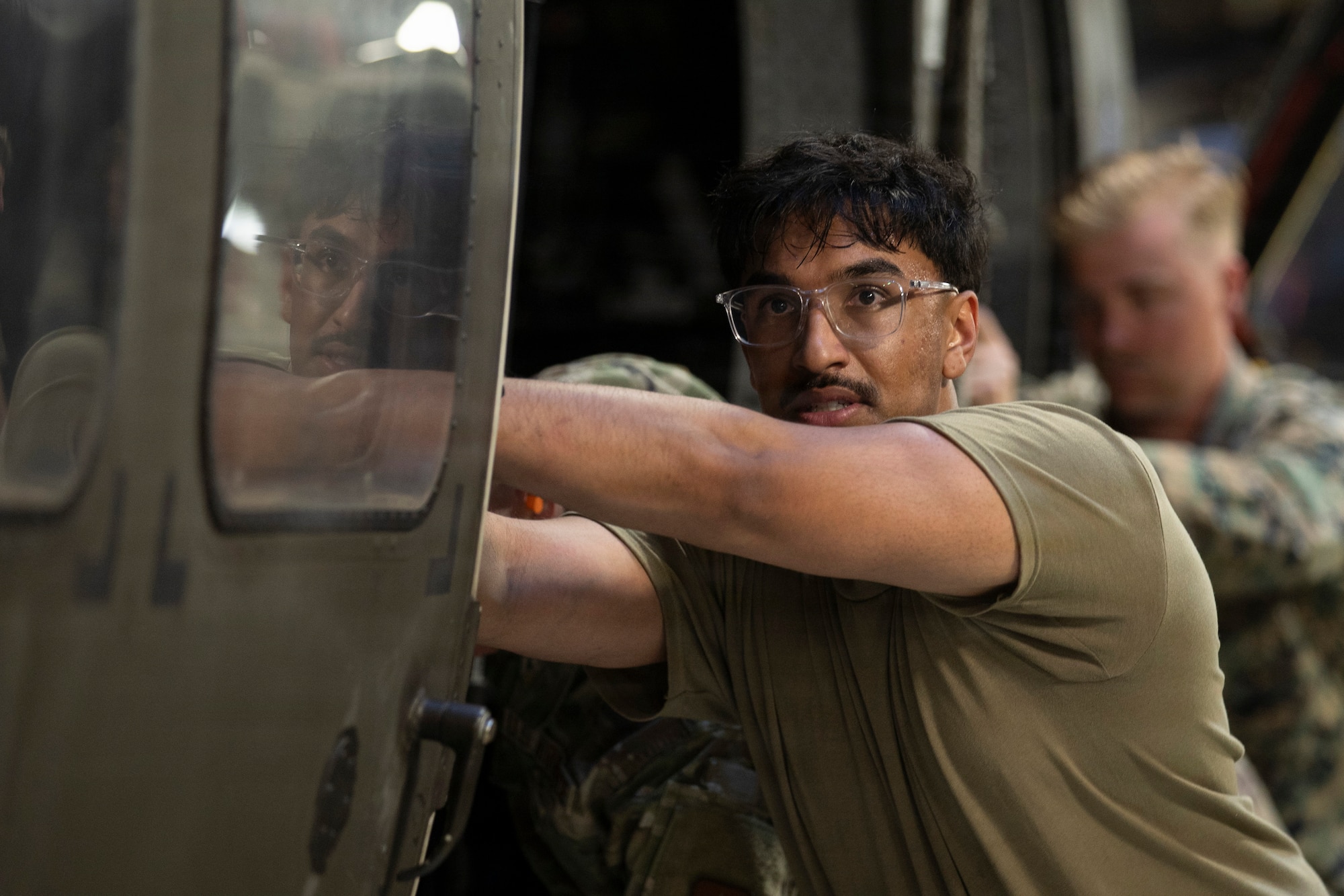 Military members push a military helicopter