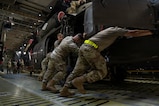 Military members push a military helicopter