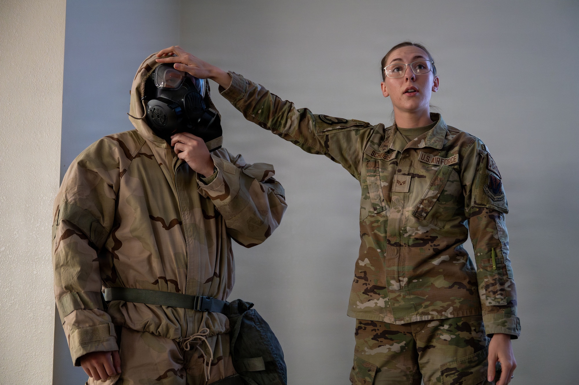 U.S. Air Force Senior Airman Jonathan Kim and Senior Airman Lydia Schubert, 355th Civil Engineer Squadron emergency management technicians, explain the importance of properly sealing mission oriented protective posture gear to Airmen attending Phase I Mission Ready Airman training at Davis-Monthan Air Force Base, Arizona, March 20, 2026. As part of a newly implemented 355th Wing initiative, Airmen eligible for their first combat zone deployment are trained to ensure mission success in any situation they could encounter down-range. (U.S. Air Force photo by Senior Airman Jasmyne Bridgers-Matos)