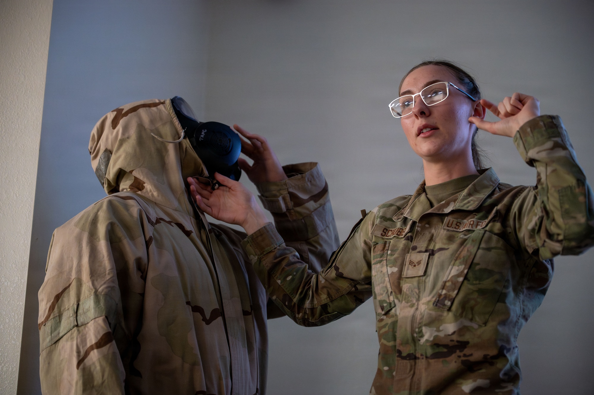 U.S. Air Force Senior Airman Jonathan Kim and Senior Airman Lydia Schubert, 355th Civil Engineer Squadron emergency management technicians, explain how to properly fit filters onto a gas mask to Airmen attending Phase I Mission Ready Airman training at Davis-Monthan Air Force Base, Arizona, March 20, 2026. The training ensures first-time combat zone deployers are prepared for any situation they could encounter down-range. (U.S. Air Force photo by Senior Airman Jasmyne Bridgers-Matos)