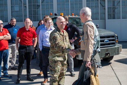 Group of people standing in front of truck on runway.