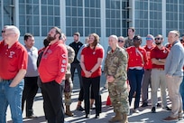 Group of people standing on tarmac and looking at sky.