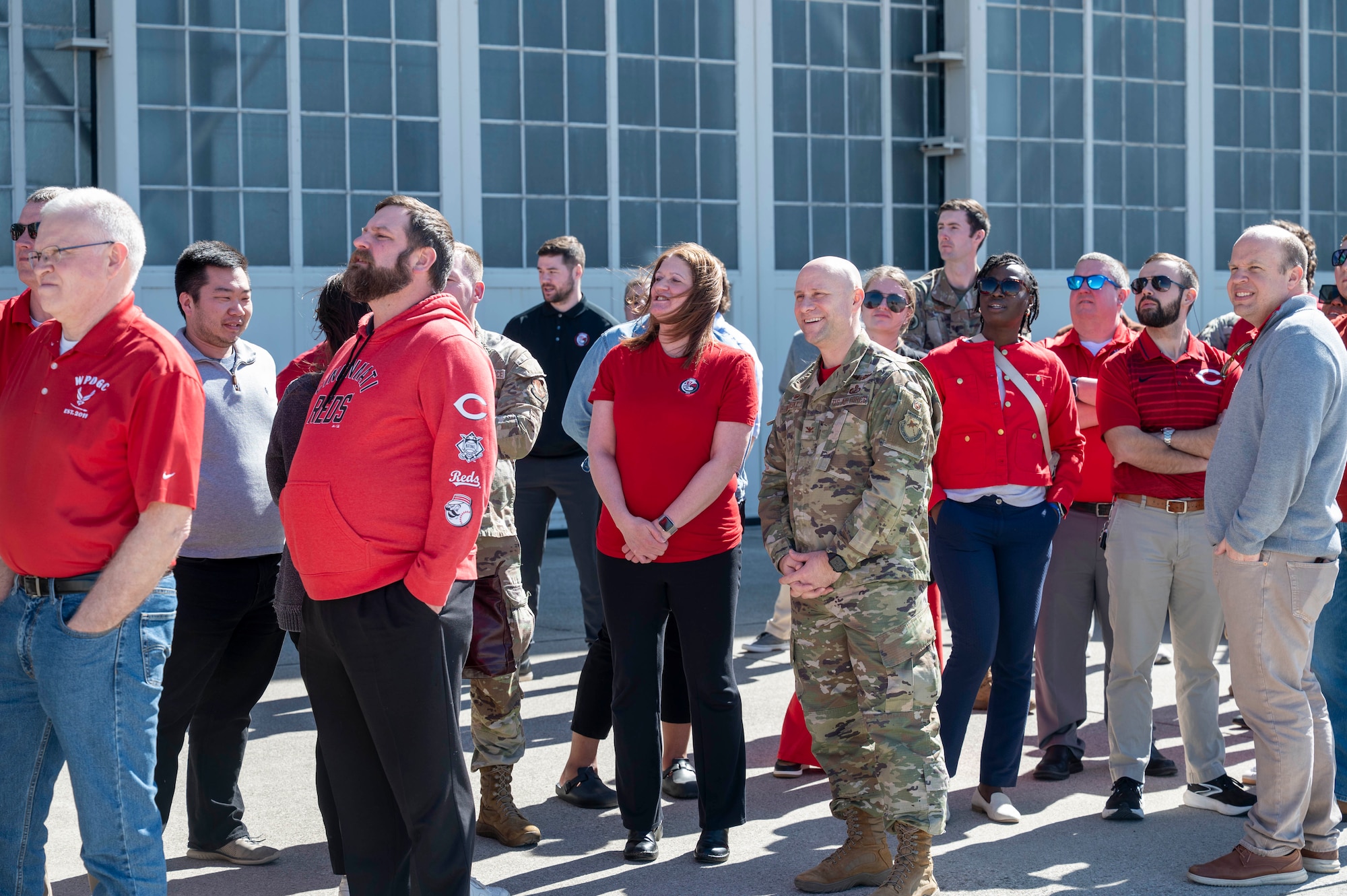 Group of people standing on tarmac and looking at sky.