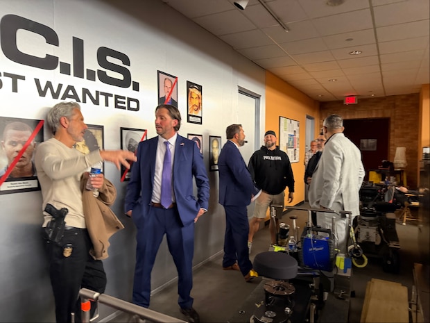Personnel from the Naval Criminal Investigation Services talk with crew from CBS' NCIS television series while visiting the set in California.