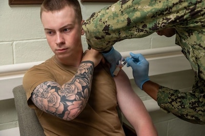 Man receives flu vaccine in upper left arm.