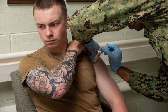 Man receives flu vaccine in upper left arm.