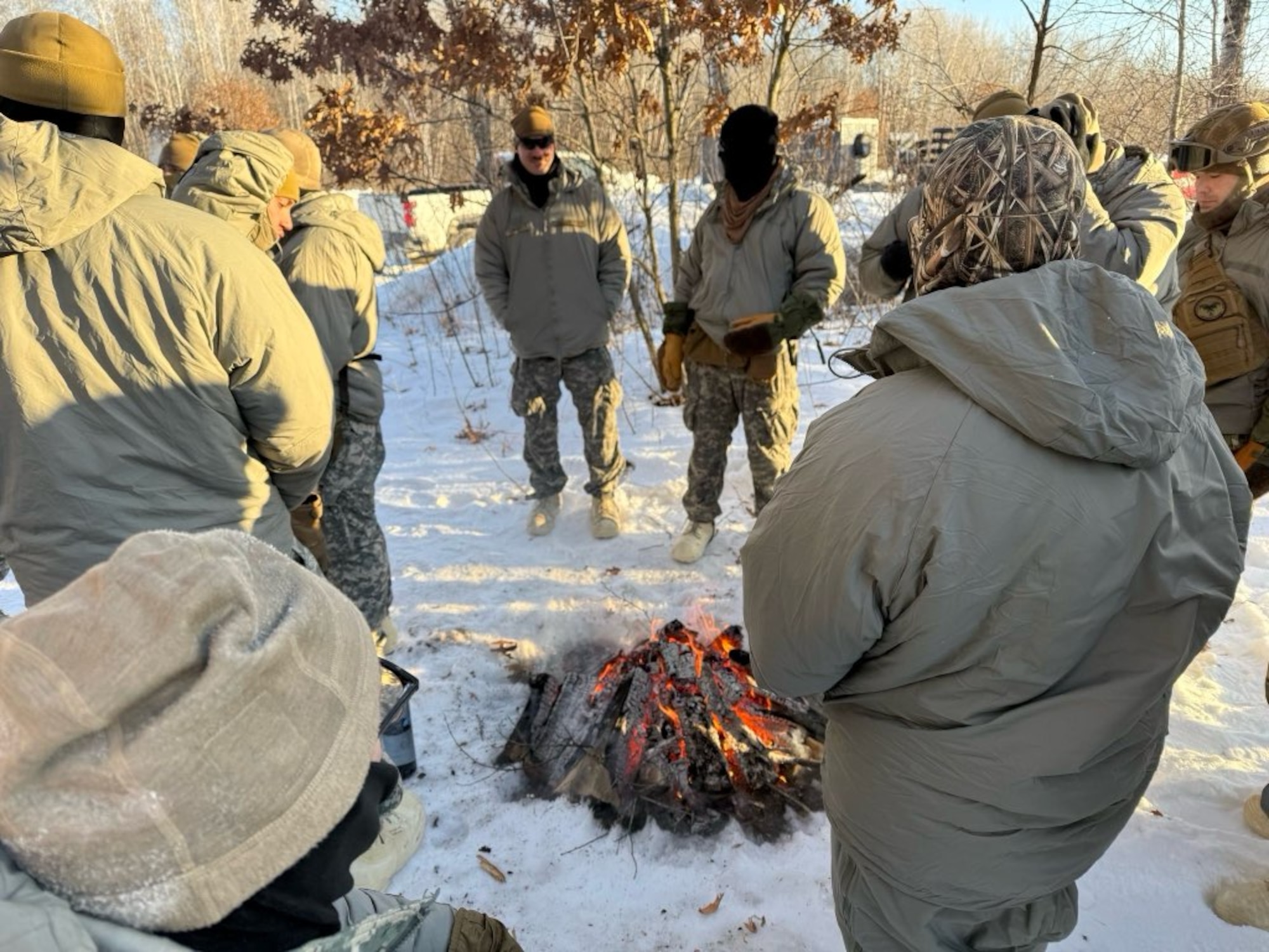 Cold weather course participants stand around a fire.