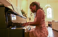 U.S. Army Spc. Aaralyn Mills, a patrol team lead with Joint Task Force - District of Columbia, plays piano before a fellow Indiana National Guard member's wedding at the Old Post Chapel on Fort Myer, Virginia, March 21, 2026. About 2,700 National Guard members support the D.C. Safe and Beautiful mission, assisting the Metropolitan Police Department in maintaining public safety for residents, commuters and visitors throughout the District.