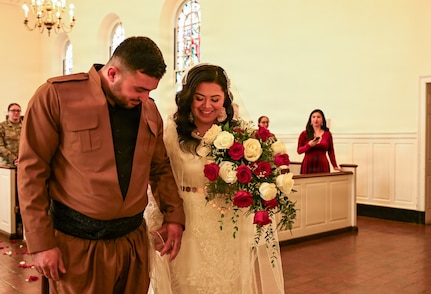 U.S. Army Spc. Ester Henriquez, an Indiana National Guard member assigned to Joint Task Force - District of Columbia, holds Hasan Alpkan's hand during their wedding ceremony at the Old Post Chapel on Fort Myer, Virginia, March 21, 2026. About 2,700 National Guard members support the D.C. Safe and Beautiful mission, assisting the Metropolitan Police Department in maintaining public safety for residents, commuters and visitors throughout the District.