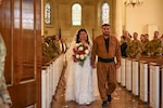 U.S. Army Spc. Ester Henriquez, an Indiana National Guard member assigned to Joint Task Force - District of Columbia, holds Hasan Alpkan's hand during their wedding ceremony at the Old Post Chapel on Joint Base Myer-Henderson Hall, Virginia, March 21, 2026. About 2,700 National Guard members support the D.C. Safe and Beautiful mission, assisting the Metropolitan Police Department in maintaining public safety for residents, commuters and visitors throughout the District. (D.C. National Guard photo by Tech. Sgt. Melissa Sterling)