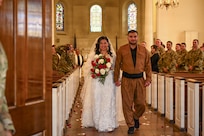 U.S. Army Spc. Ester Henriquez, an Indiana National Guard member assigned to Joint Task Force - District of Columbia, holds Hasan Alpkan's hand during their wedding ceremony at the Old Post Chapel on Joint Base Myer-Henderson Hall, Virginia, March 21, 2026. About 2,700 National Guard members support the D.C. Safe and Beautiful mission, assisting the Metropolitan Police Department in maintaining public safety for residents, commuters and visitors throughout the District.