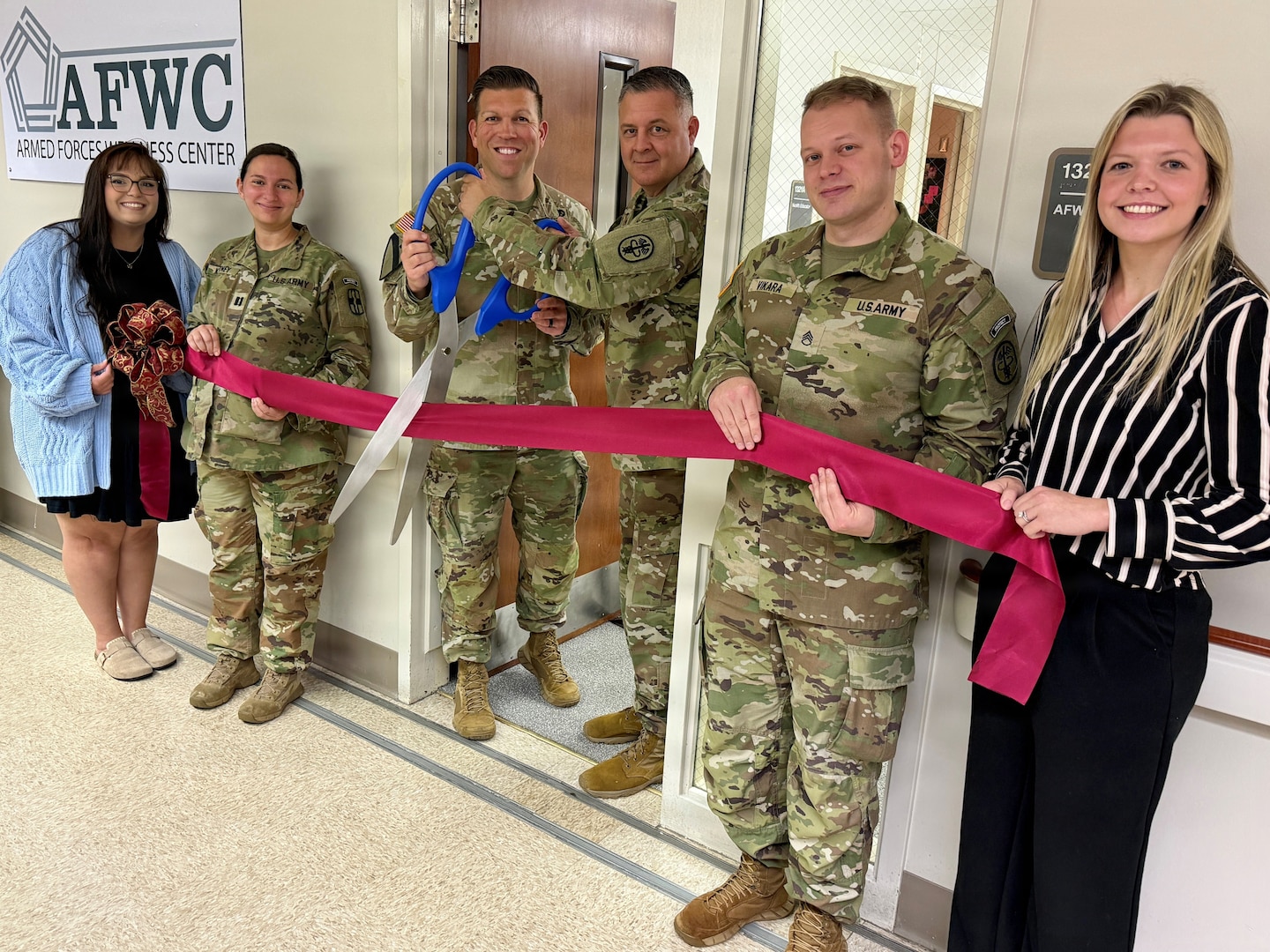 A group of Soldiers and civilians line up to cut the ribbon on the AFWC.