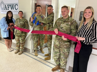 A group of Soldiers and civilians line up to cut the ribbon on the AFWC.