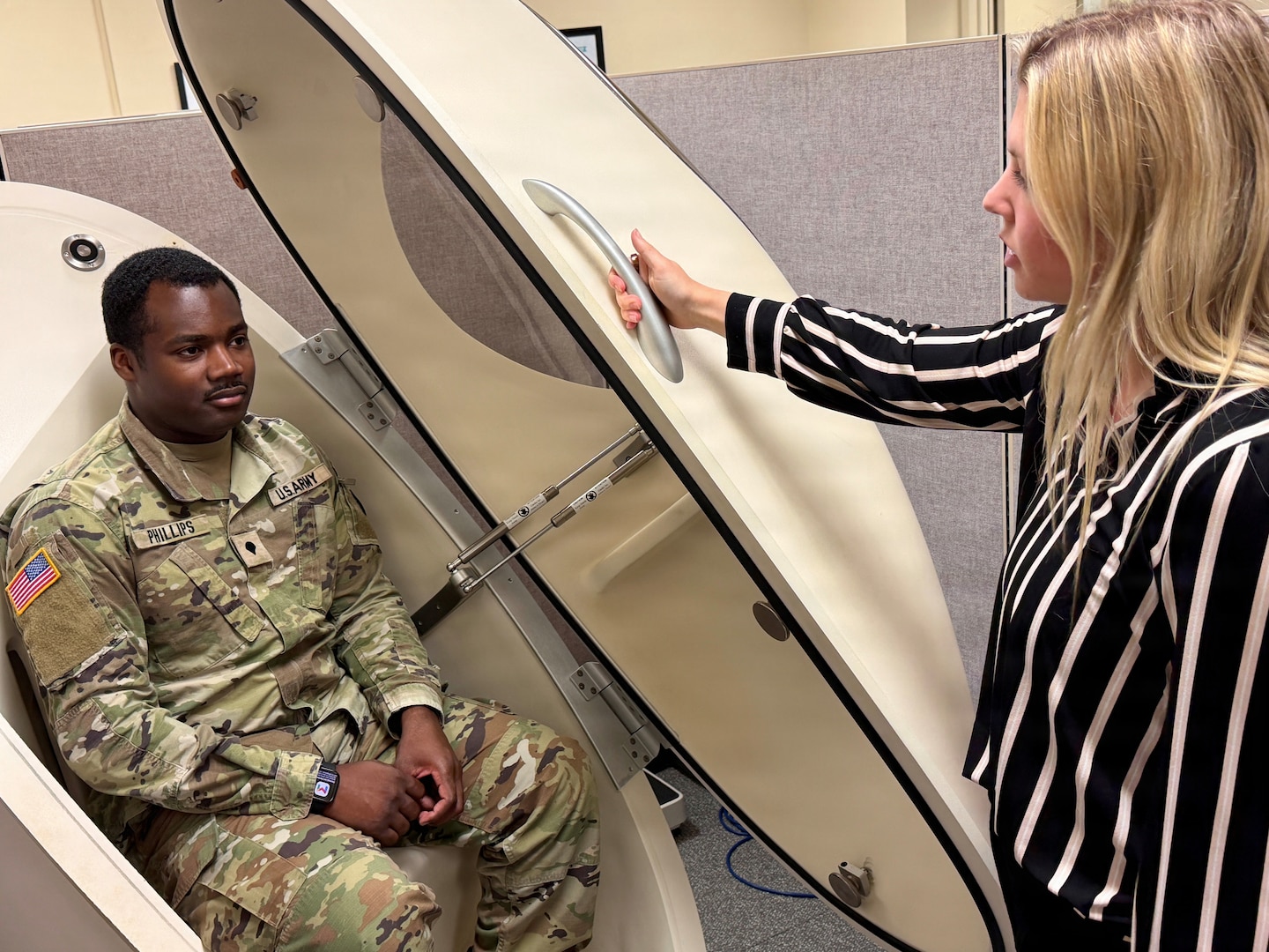 Soldier sitting in the BOD POD as a technician prepares to close the door.