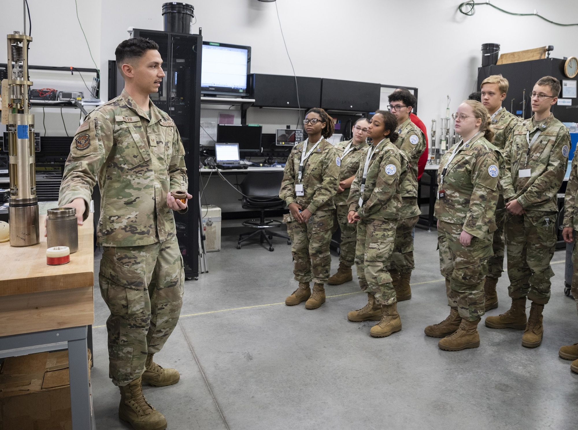 Senior Airman Niklas Miller (left), a geophysical maintenance technician in the Air Force Technical Applications Center’s Central Repair Facility at Patrick Space Force Base, Fla., briefs a group of Junior Reserve Officer Training Corps cadets from Vero Beach High School, Fla., during their visit to the center March 17, 2026. The cadets were given the opportunity to learn more about how AFTAC conducts its global nuclear surveillance mission.  (U.S. Air Force photo by Matthew S. Jurgens)