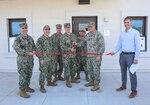 A group of military personnel use large scissors to cut a ceremonial ribbon.
