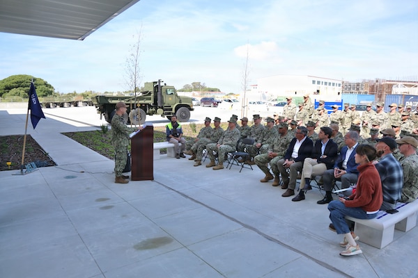 Capt. Chmielak stands at a podium and speaks to a crowd of personnel in uniform.
