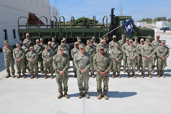 Sailors in uniform stand in formation for a photo.