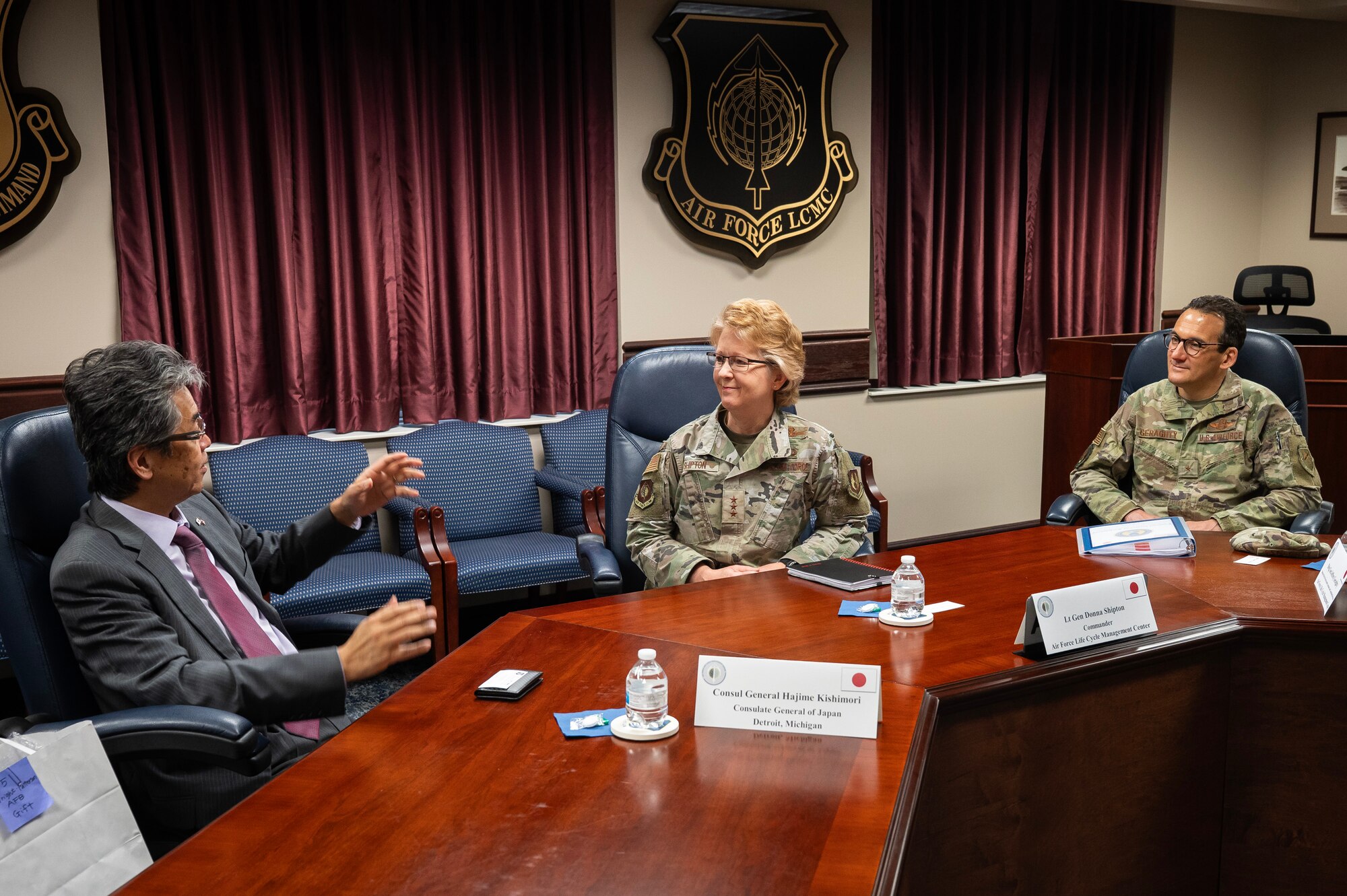 Man in business suit talks with female and male Air Force officers.