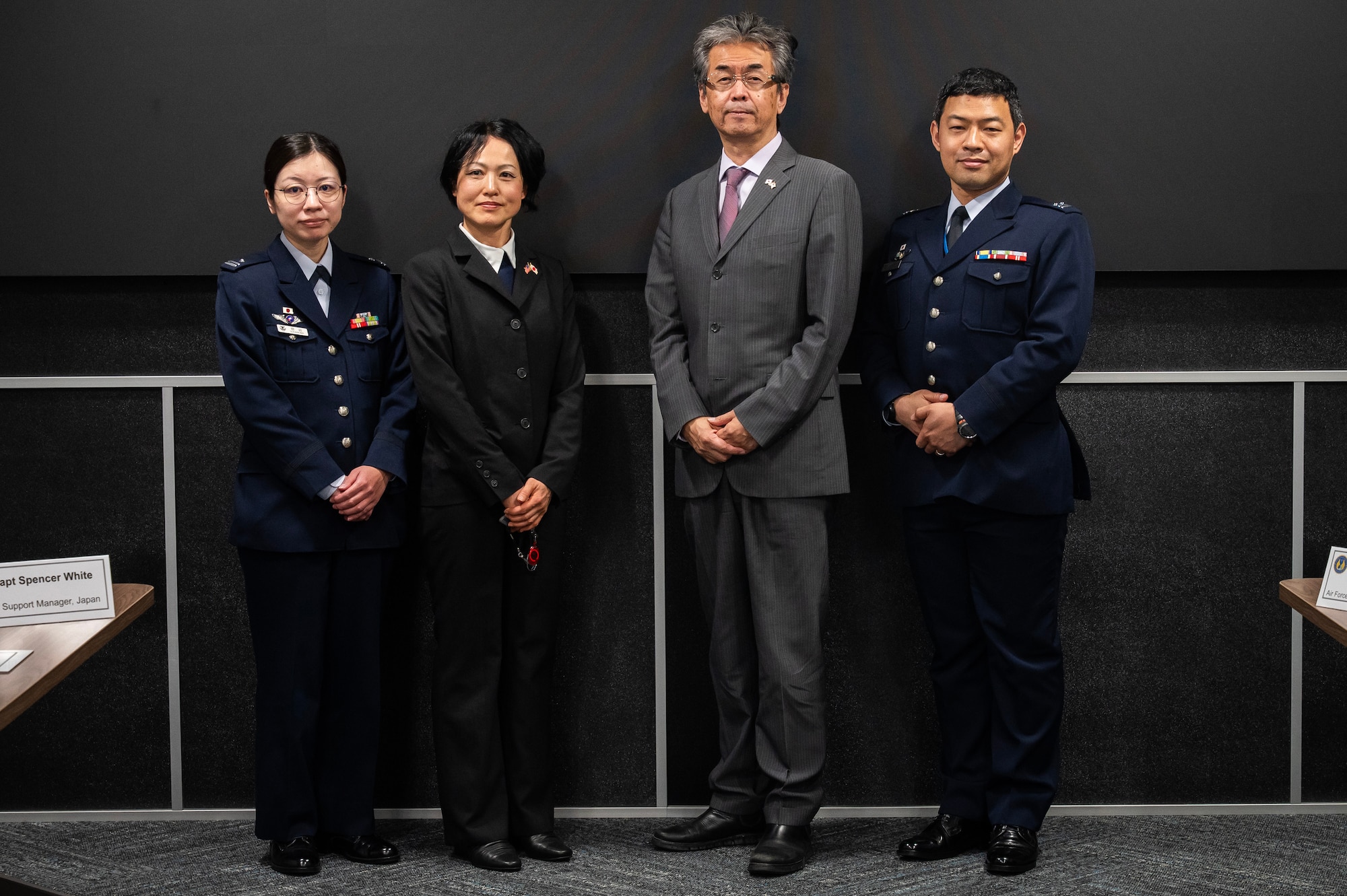 Four individuals standing and pose for photos. Wearing dark suits or Japanese military uniforms.