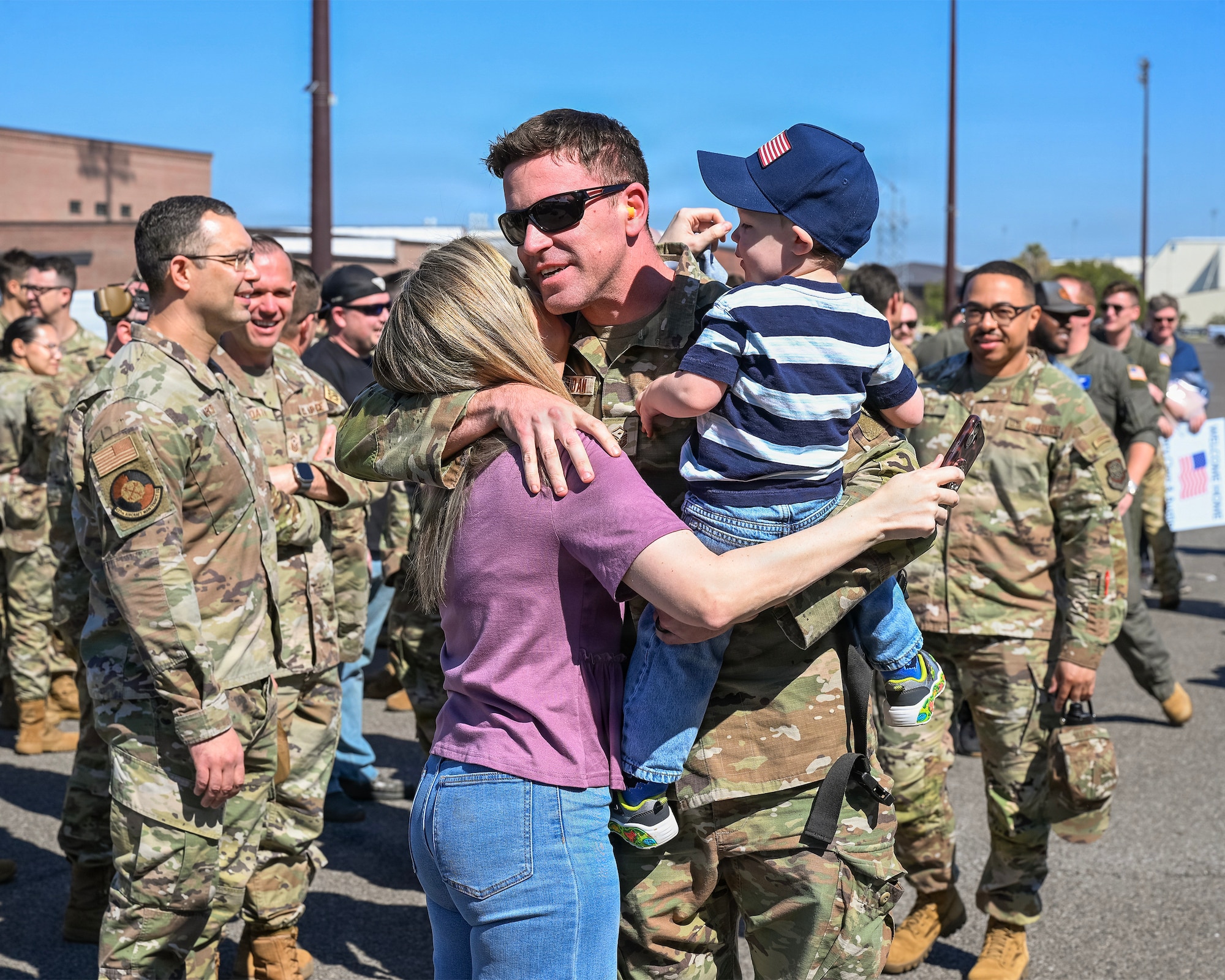 An Airman holds his family in a crowd.