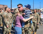 An Airman holds his family in a crowd.