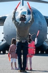 A man and two young girls air marshal in a C-17 Globemaster III aircraft on a flightline.
