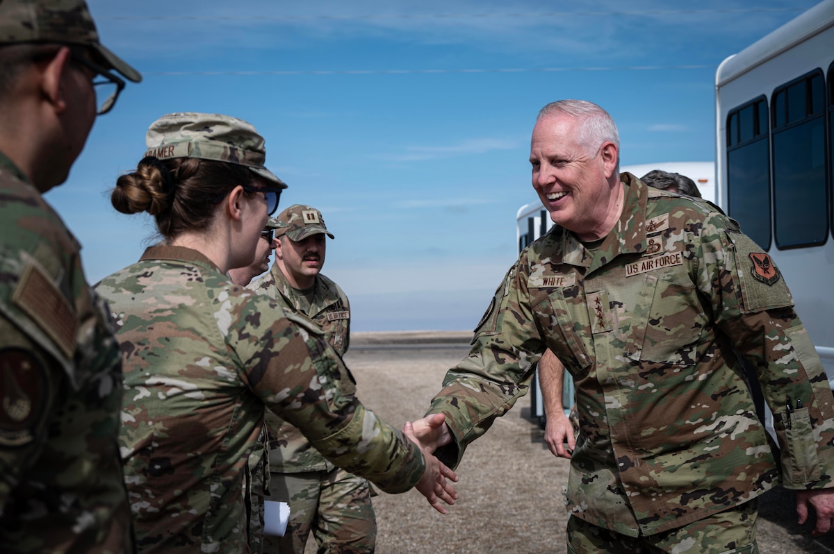 U.S. Air Force Gen. Dale R. White greets an Airman with a handshake.