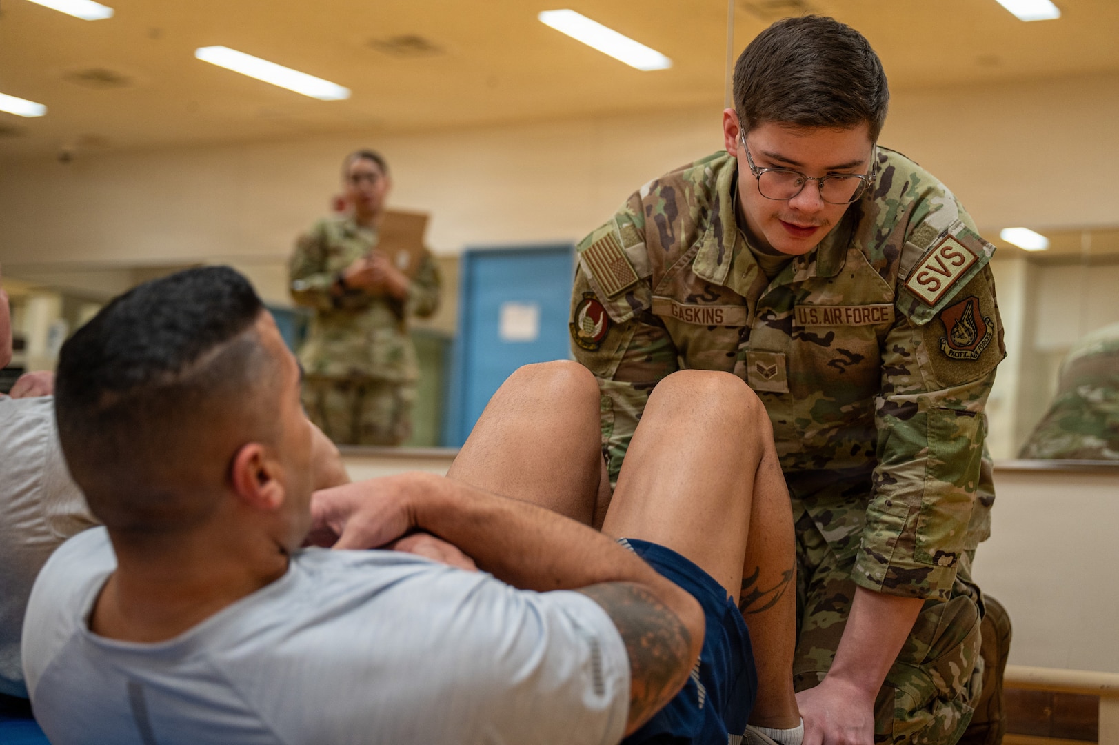 Senior Airman Mason Gaskins, 374th Force Support Squadron sports and fitness shift leader, holds the feet of U.S. Air Force Chief Master Sgt. Carlos Damian, U.S. Forces Japan command senior enlisted leader, while he performs sit-ups during a diagnostic physical fitness readiness assessment at Yokota Air Base, Japan, March 11, 2026.