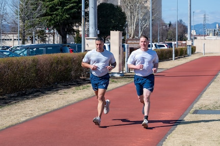 U.S. Air Force Chief Master Sergeants Carlos Damian (left), U.S. Forces Japan command senior enlisted leader, and Cole Reinbold, 36th Airlift Squadron SEL, perform a two-mile run during a diagnostic physical fitness readiness assessment at Yokota Air Base, Japan, March 11, 2026.