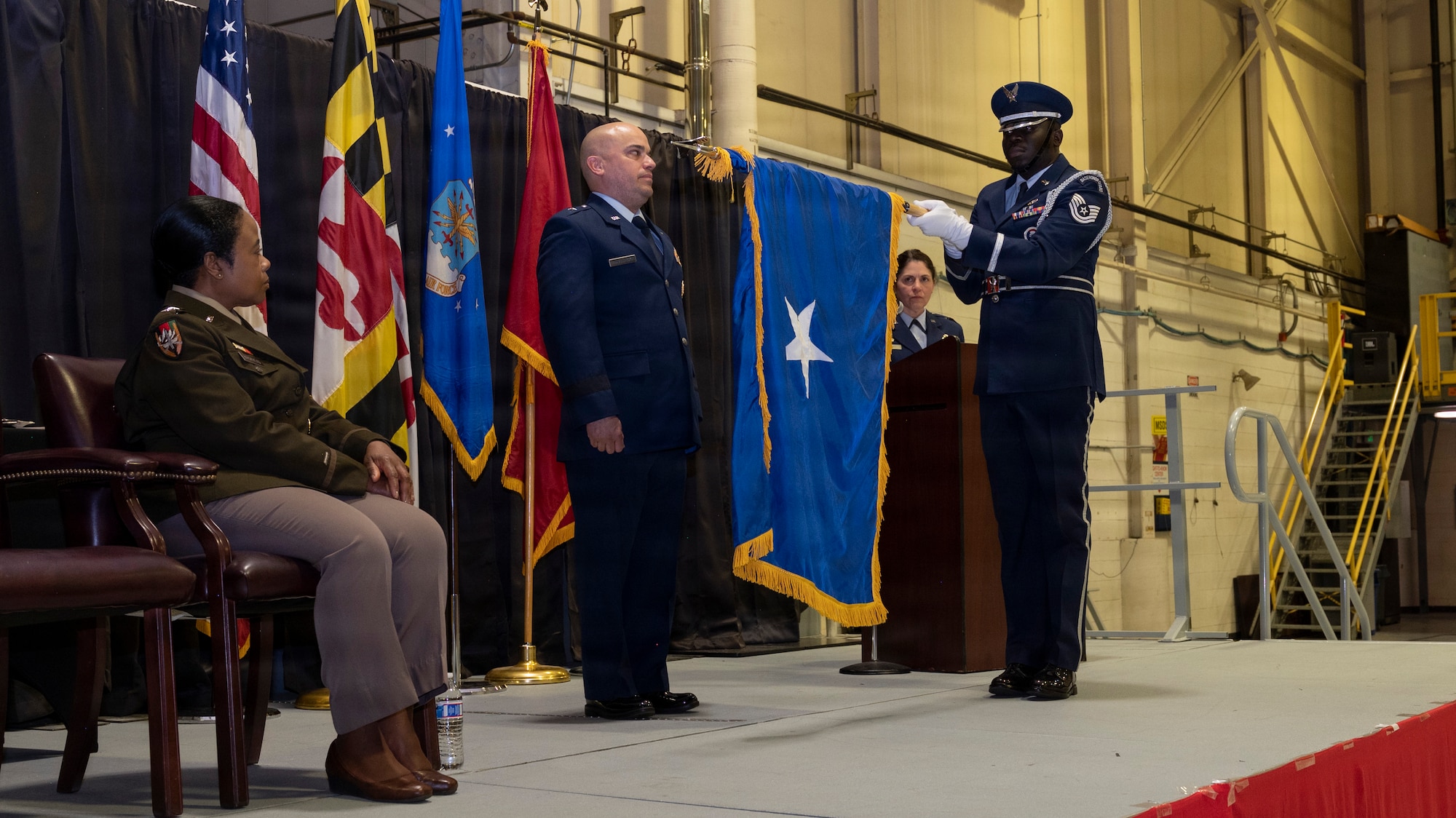 Maryland Air National Guard Col. Joed Carbonell-López, commander of the 175th Wing, stands during his flag unfurling and is promoted to brigadier general by Maryland Army National Guard Maj. Gen. Janeen Birckhead, adjutant general for Maryland, during a ceremony at Warfield Air National Guard Base at Martin State Airport, Maryland, March 22, 2026. In his role as wing commander, Carbonell-López oversees more than 1,400 personnel across three operations groups, one mission support group, one medical group, and one civil engineering element. (U.S. Air National Guard photo by Staff Sgt. Alexandra Huettner)