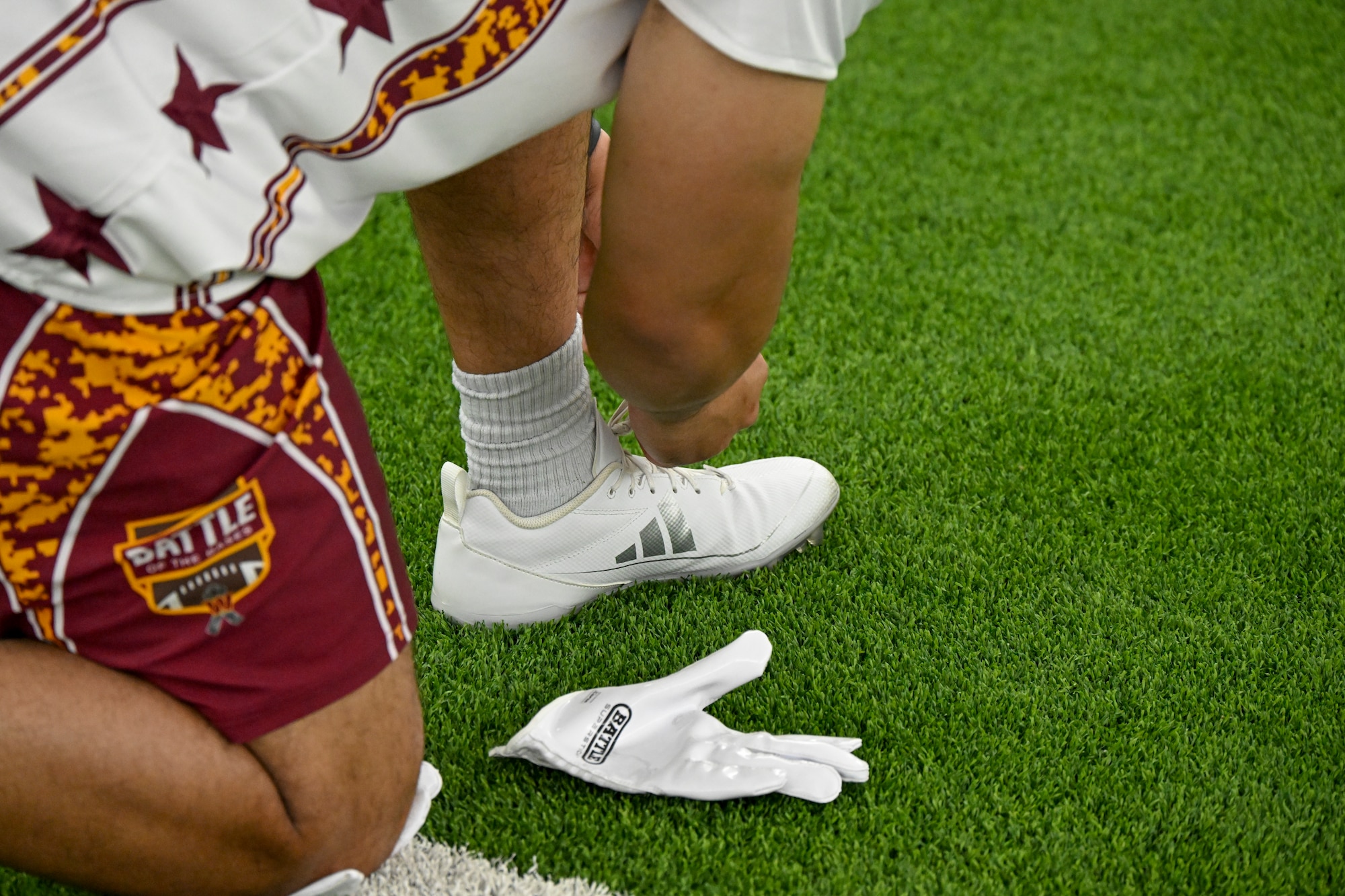 A participant from Joint Base Anacostia-Bolling ties his shoe before competing in the Battle of the Bases flag football tournament.