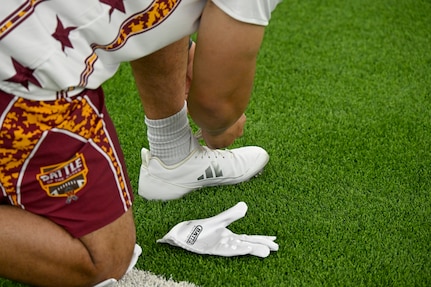 A participant from Joint Base Anacostia-Bolling ties his shoe before competing in the Battle of the Bases flag football tournament.
