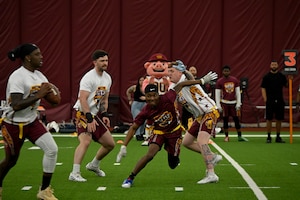 An athlete from Joint Base Andrews breaks through the line to reach the quarterback at the Battle of the Bases flag football tournament.