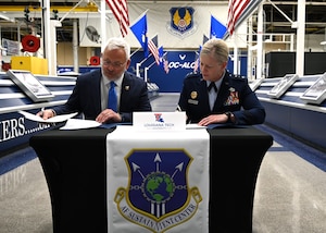 A civilian and military leader signing an agreement.