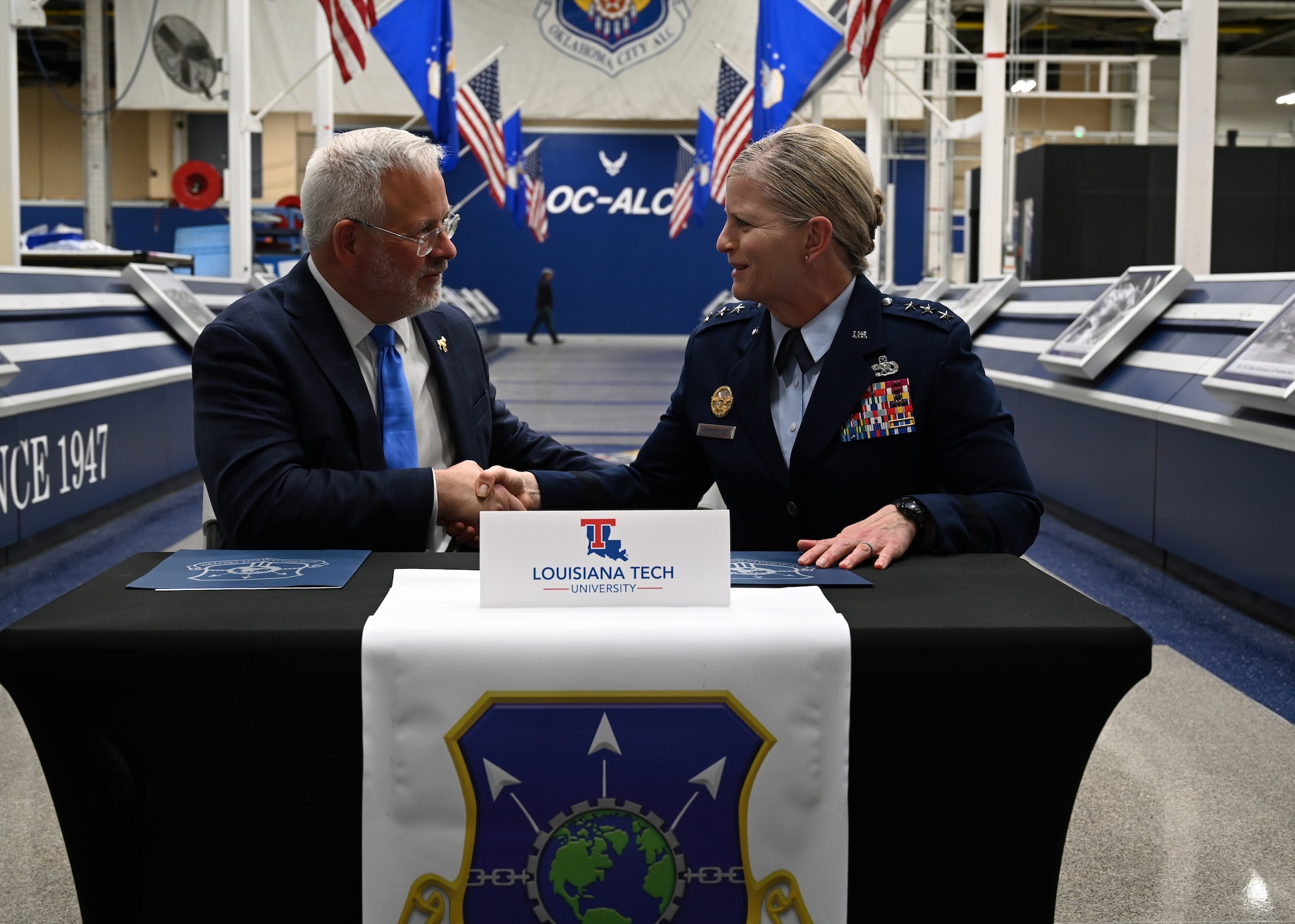 A civilian and military leader signing an agreement.