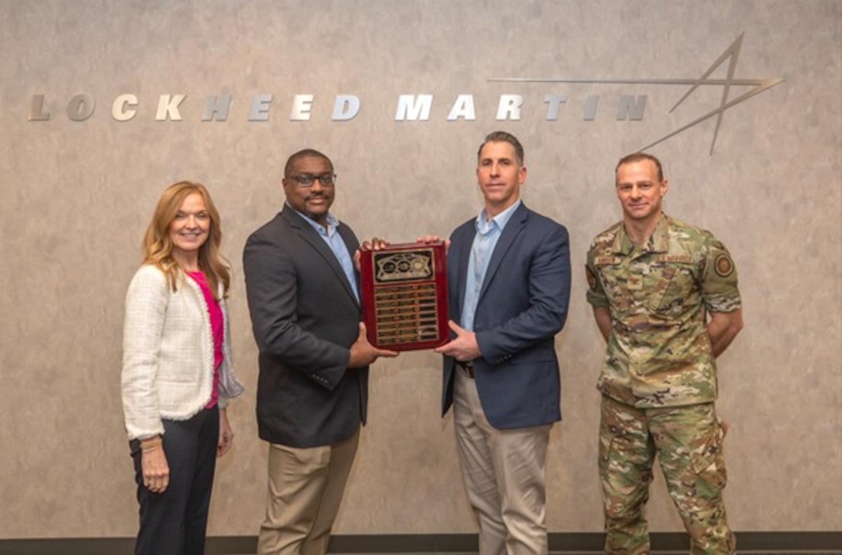 Four people pose for a photo with middle two people holding an award